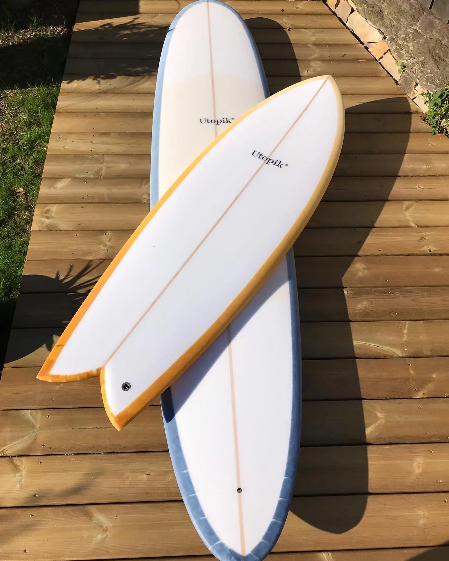 Deux Retro Fish Utopik blancs et safran vus ensemble sur une terrasse en bois